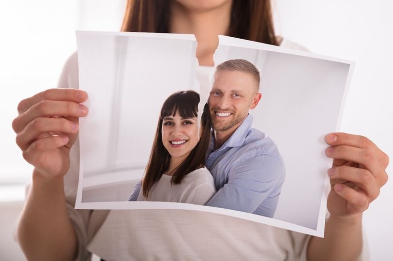 Woman's hand tearing photograph of ex