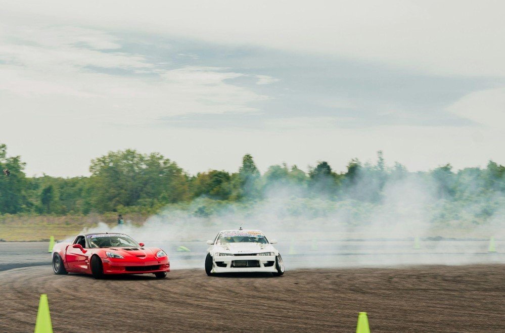 couple of cars driving down a mud road